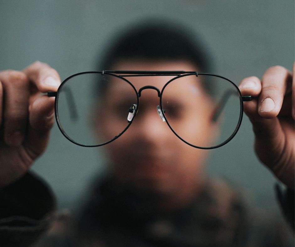 man holding up and looking through glasses